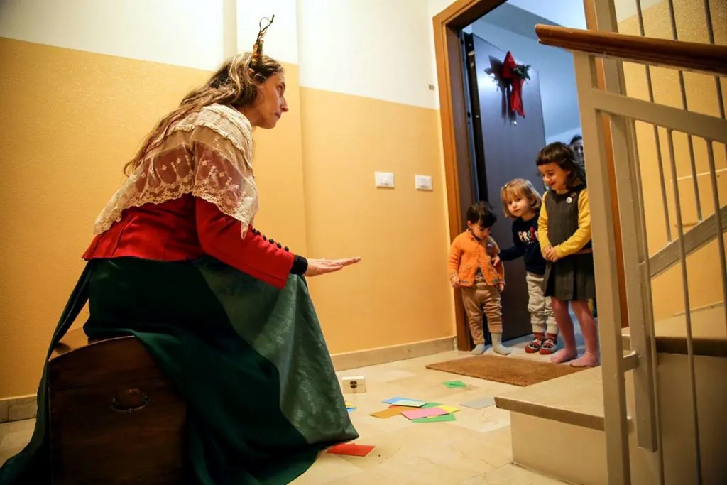 L’attrice Alessandra Amerio della compagnia modenese Peso Specifico Teatro, incanta dei bambini sulla soglia di una porta, durante una performance di Teatro Express