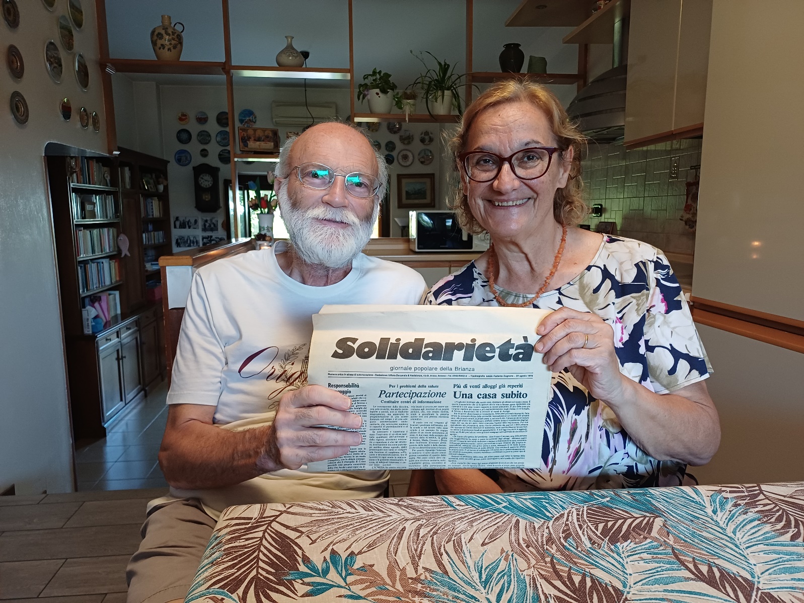 I coniugi Alfredo Spagnuolo e Dina Colombini, seduti al tavolo di casa, mostrano una copia ingiallita del giornale Solidarietà del 1976.